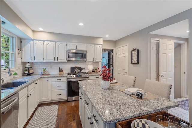 9607 Dunderry, Lysander, NY 13027 - kitchen with appliances with stainless steel finishes, a kitchen bar, light stone countertops, white cabinetry, and recessed lighting