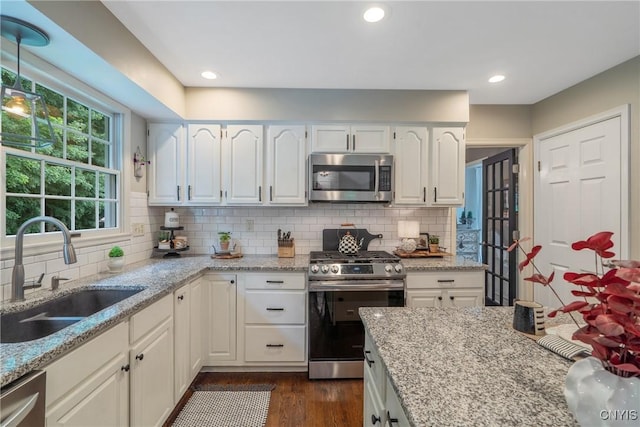 9607 Dunderry, Lysander, NY 13027 - kitchen featuring appliances with stainless steel finishes, light stone countertops, white cabinetry, decorative backsplash, and dark wood-style floors