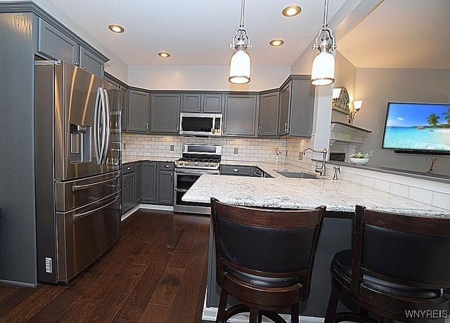 114 Slate Bottom Dr, Lancaster, NY 14043 - kitchen with appliances with stainless steel finishes, a peninsula, dark wood-type flooring, gray cabinetry, and recessed lighting