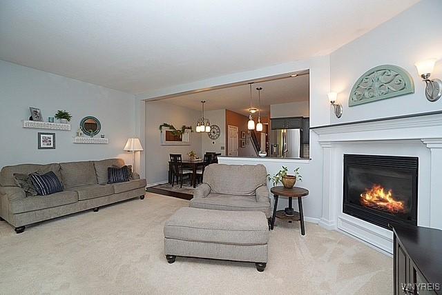 114 Slate Bottom Dr, Lancaster, NY 14043 - carpeted living area with a chandelier and a glass covered fireplace