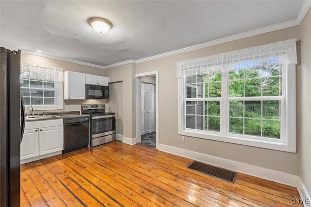 17 Burr St, Cazenovia, NY 13035 - kitchen with black appliances, white cabinetry, light wood-style flooring, crown molding, and healthy amount of natural light
