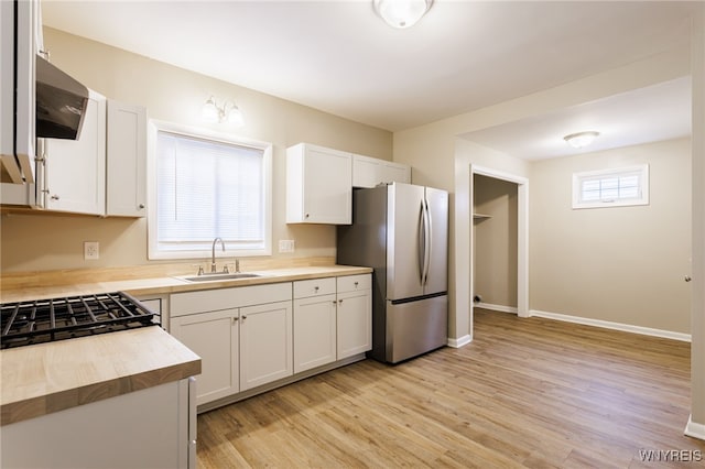 708 Garson Ave, Rochester, NY 14609 - kitchen with freestanding refrigerator, butcher block countertops, light wood finished floors, white cabinets, and range hood