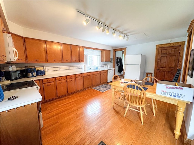 80 E Main St, Leroy, NY 14482 - kitchen with white appliances, track lighting, brown cabinetry, light countertops, and light wood-style flooring