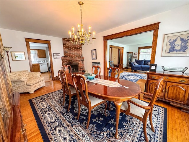 80 E Main St, Leroy, NY 14482 - dining space featuring a chandelier, light wood-style flooring, and a brick fireplace