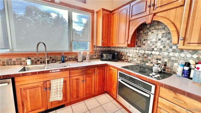 7320 E Flats Rd, East Otto, NY 14729 - kitchen featuring stainless steel appliances, tasteful backsplash, light tile patterned floors, and brown cabinets