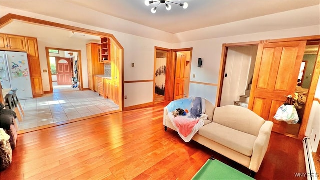 7320 E Flats Rd, East Otto, NY 14729 - living room featuring a baseboard radiator, light wood-type flooring, a chandelier, and arched walkways