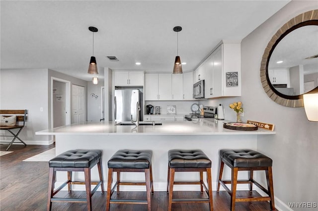 803 Admirals Walk Unit 803, Buffalo, NY 14202 - kitchen with appliances with stainless steel finishes, a peninsula, light countertops, hanging light fixtures, and dark wood-style flooring