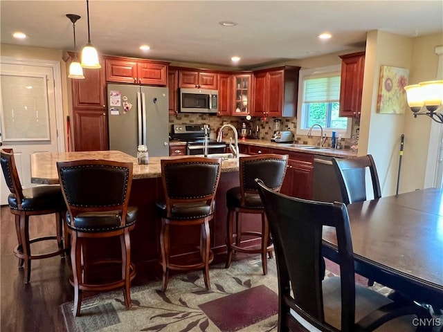 206 Wembridge Dr, Dewitt, NY 13057 - kitchen featuring appliances with stainless steel finishes, an island with sink, tasteful backsplash, pendant lighting, and glass insert cabinets