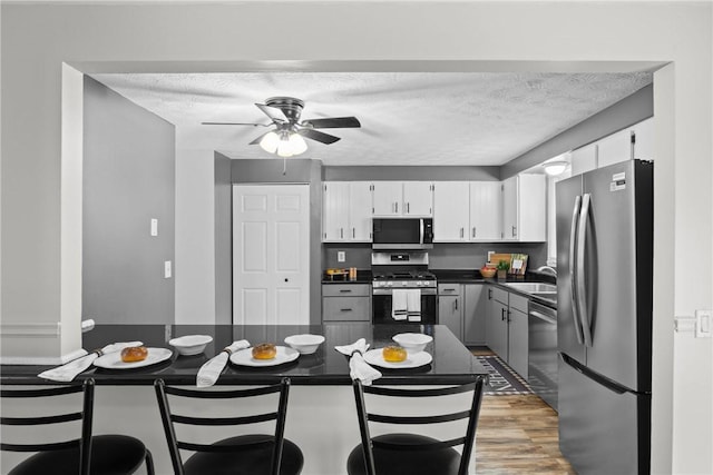 911 Copperkettle Rd, Webster, NY 14580 - kitchen featuring stainless steel appliances, dark countertops, a ceiling fan, light wood finished floors, and white cabinets