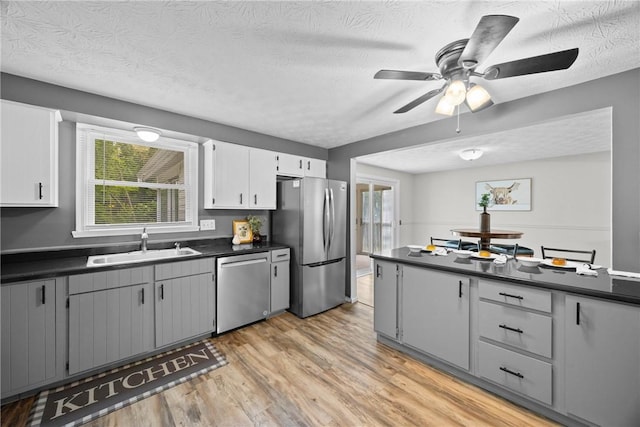 911 Copperkettle Rd, Webster, NY 14580 - kitchen featuring stainless steel appliances, dark countertops, light wood-style flooring, plenty of natural light, and a textured ceiling