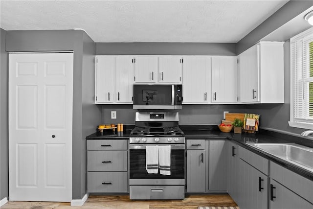 911 Copperkettle Rd, Webster, NY 14580 - kitchen featuring appliances with stainless steel finishes, dark countertops, light wood-type flooring, white cabinets, and gray cabinets