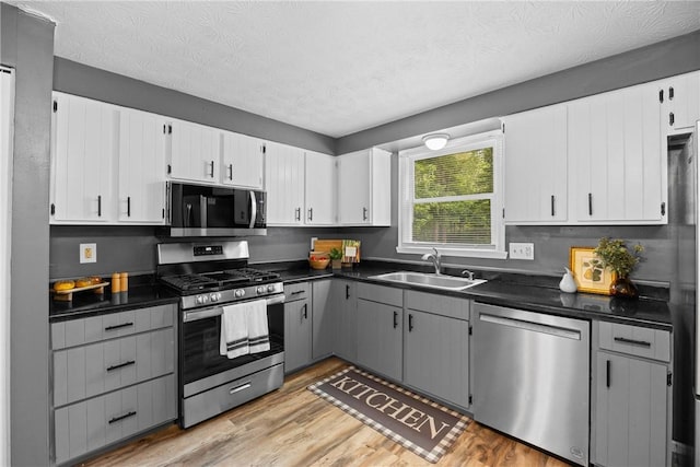 911 Copperkettle Rd, Webster, NY 14580 - kitchen featuring appliances with stainless steel finishes, dark countertops, light wood-style floors, a textured ceiling, and white cabinets