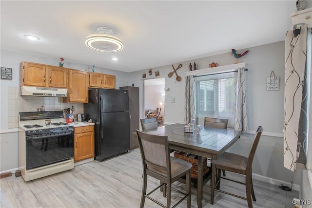 217 Melrose Ave, Camillus, NY 13219 - kitchen featuring white gas stove, freestanding refrigerator, under cabinet range hood, decorative backsplash, and light countertops