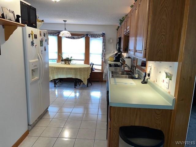 208 Angle Rd, West Seneca, NY 14224 - kitchen with white refrigerator with ice dispenser, light tile patterned flooring, light countertops, range, and hanging light fixtures