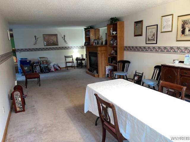 208 Angle Rd, West Seneca, NY 14224 - dining space featuring a fireplace, carpet flooring, and a textured ceiling