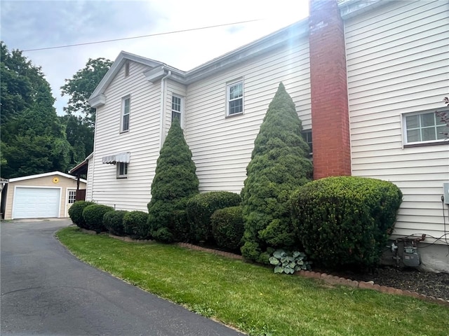 73 Platt St, Hornell, NY 14843 - view of home's exterior with an outdoor structure, a detached garage, driveway, and a chimney