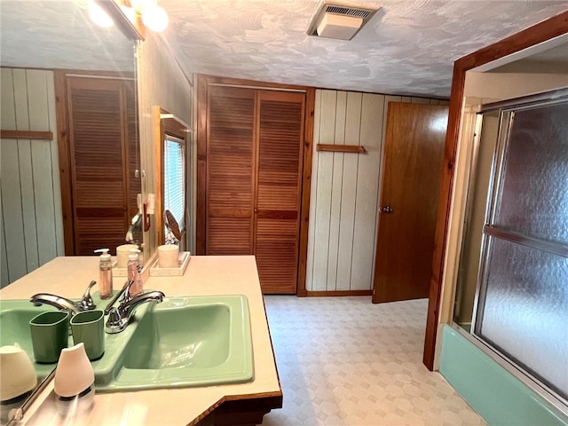 73 Platt St, Hornell, NY 14843 - bathroom with a shower with shower door, wood walls, tile patterned floors, vanity, and a closet