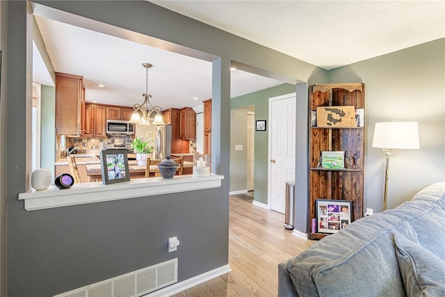 15 Chesapeake Lndg, Henrietta, NY 14586 - kitchen with stainless steel appliances, open floor plan, brown cabinetry, decorative backsplash, and light wood-style flooring