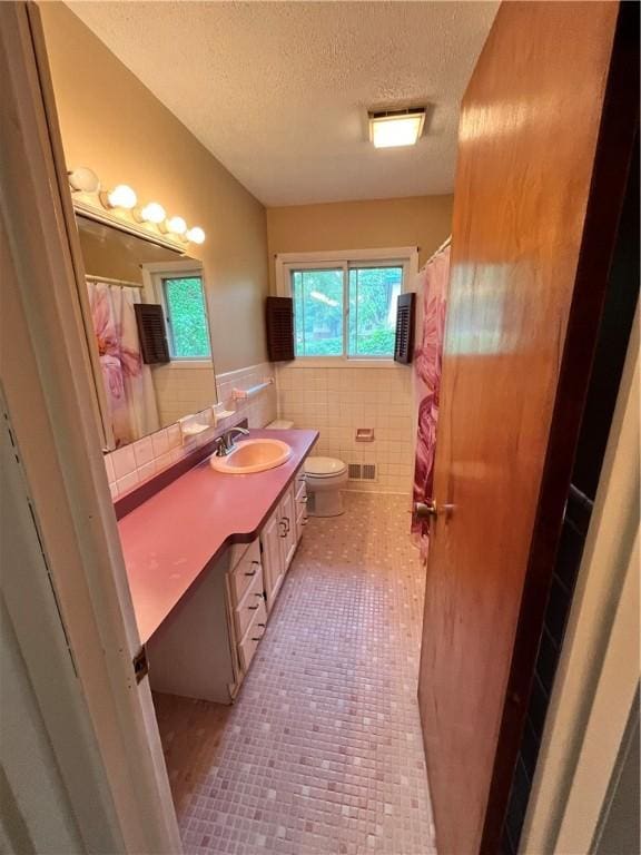 96 Vinal Ave, Irondequoit, NY 14609 - bathroom with tile patterned floors, vanity, tile walls, a textured ceiling, and a wainscoted wall