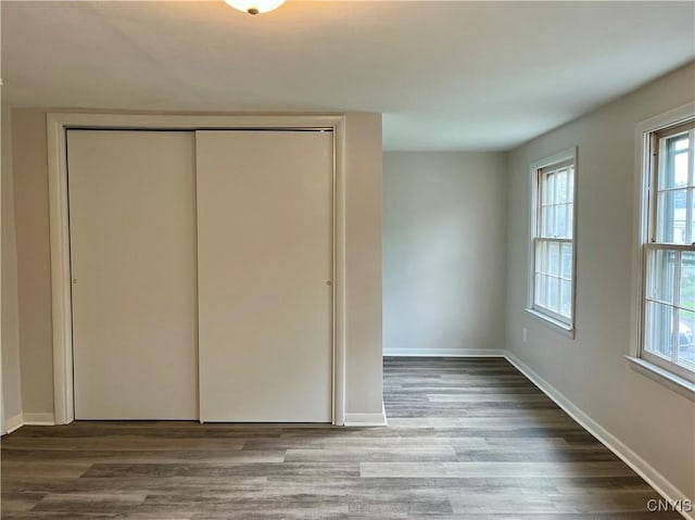 152 W Cayuga St, Oswego, NY 13126 - unfurnished bedroom featuring a closet, wood finished floors, and multiple windows