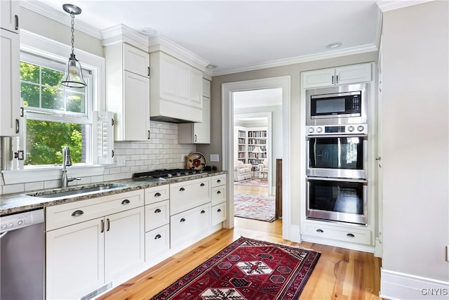 49 Academy St, Skaneateles, NY 13152 - kitchen with stainless steel appliances, light wood-style flooring, backsplash, white cabinetry, and decorative light fixtures