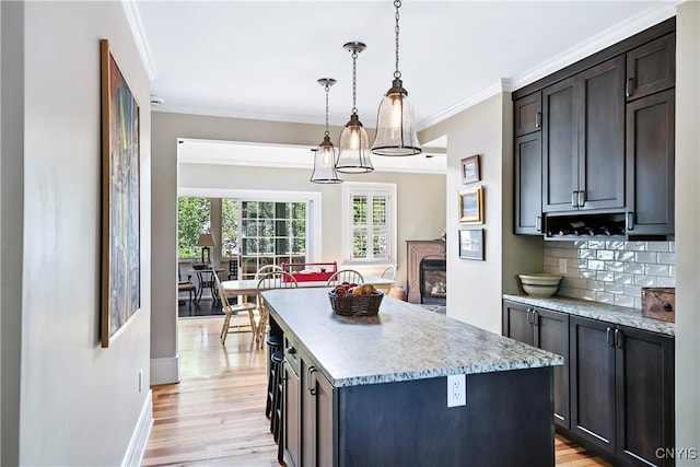 49 Academy St, Skaneateles, NY 13152 - kitchen with light wood-type flooring, tasteful backsplash, a center island, ornamental molding, and pendant lighting