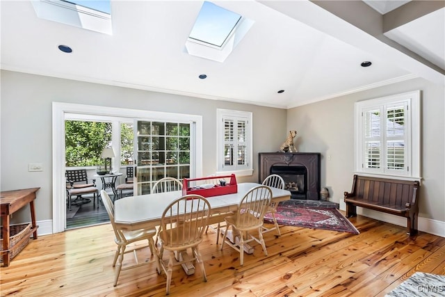 49 Academy St, Skaneateles, NY 13152 - dining space with a skylight, light wood-style floors, ornamental molding, vaulted ceiling, and a glass covered fireplace