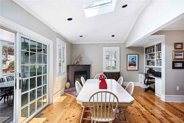 49 Academy St, Skaneateles, NY 13152 - dining area featuring light wood-style floors, a glass covered fireplace, ornamental molding, a skylight, and recessed lighting