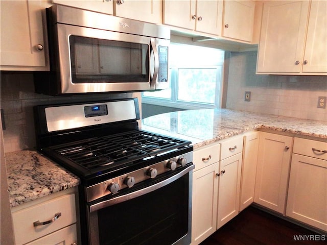 4315 Twilight Ln, Hamburg, NY 14075 - kitchen featuring appliances with stainless steel finishes, tasteful backsplash, light stone countertops, white cabinets, and dark wood-type flooring
