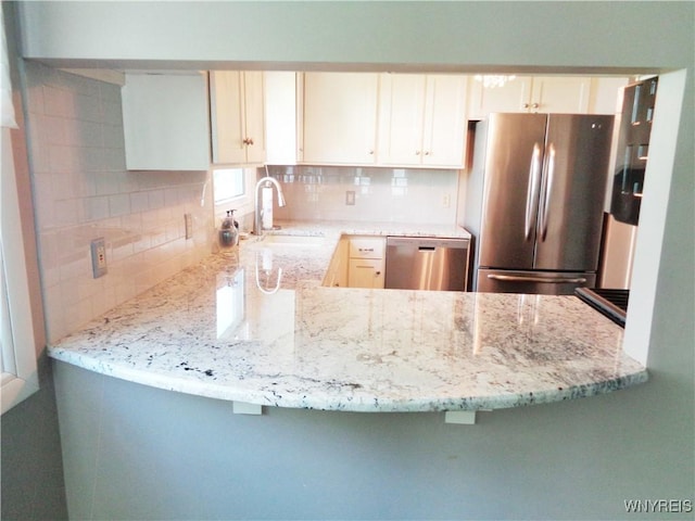 4315 Twilight Ln, Hamburg, NY 14075 - kitchen featuring appliances with stainless steel finishes, tasteful backsplash, light stone countertops, a peninsula, and white cabinetry
