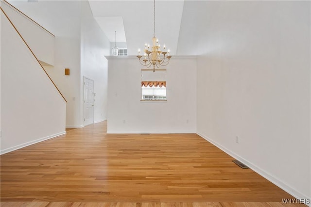 25 Caspian Ct, Amherst, NY 14228 - unfurnished dining area featuring a chandelier, a high ceiling, light wood-style flooring, and stairway