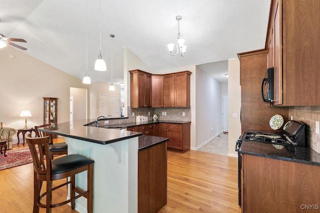 8449 Newbury Pl, Clay, NY 13041 - kitchen with black appliances, vaulted ceiling, a breakfast bar, a peninsula, and backsplash