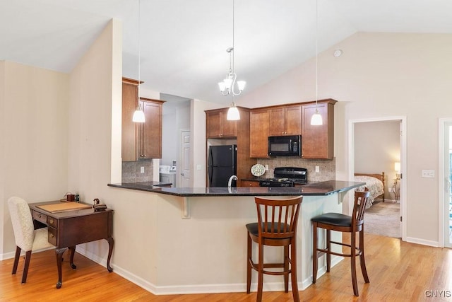 8449 Newbury Pl, Clay, NY 13041 - kitchen with black appliances, vaulted ceiling, a breakfast bar area, a peninsula, and brown cabinets
