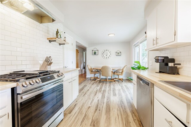 118 Fern Castle Dr, Irondequoit, NY 14622 - kitchen featuring stainless steel appliances, light wood-style flooring, white cabinets, backsplash, and wooden counters