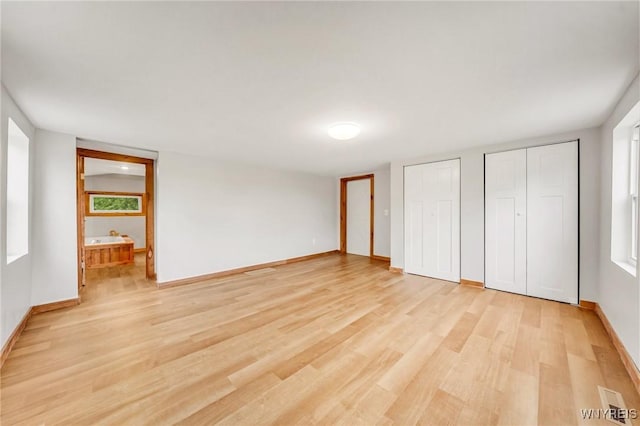 10655 Millers Rd, Yates, NY 14098 - unfurnished bedroom featuring two closets, light wood-style floors, and connected bathroom