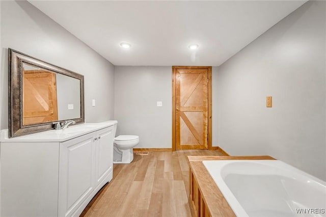 10655 Millers Rd, Yates, NY 14098 - bathroom with vanity, a bath, wood finished floors, and recessed lighting