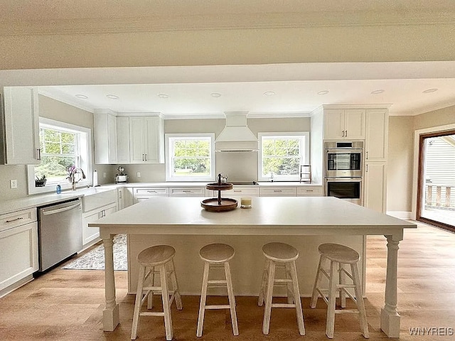 10448 Clarence Center Rd, Clarence, NY 14031 - kitchen featuring stainless steel appliances, custom exhaust hood, a kitchen island, a breakfast bar, and ornamental molding