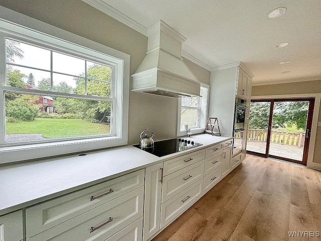 10448 Clarence Center Rd, Clarence, NY 14031 - kitchen with custom exhaust hood, black electric stovetop, crown molding, plenty of natural light, and wood finished floors