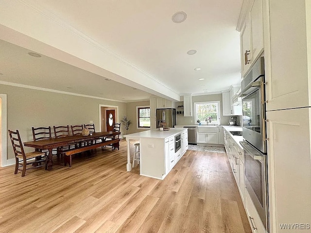 10448 Clarence Center Rd, Clarence, NY 14031 - kitchen with stainless steel appliances, a kitchen island, light wood-type flooring, a kitchen breakfast bar, and crown molding