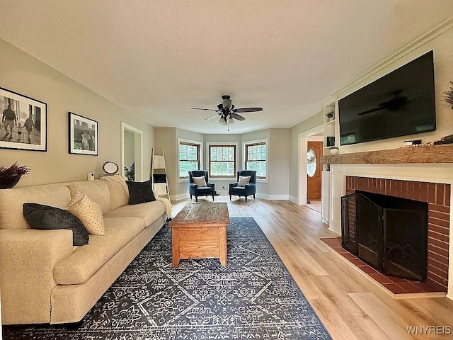10448 Clarence Center Rd, Clarence, NY 14031 - living room featuring light wood finished floors, a ceiling fan, a fireplace, and a textured ceiling