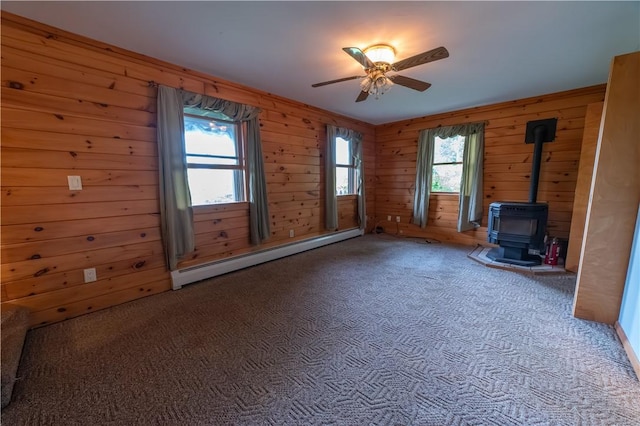 817 Flax Island Rd, Otego, NY 13825 - unfurnished living room featuring a baseboard radiator, carpet flooring, a wood stove, a ceiling fan, and wooden walls