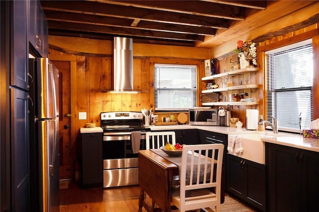5681 Leidenfrost Adams Rd, Hector, NY 14841 - kitchen featuring appliances with stainless steel finishes, wall chimney exhaust hood, light countertops, wood finished floors, and beamed ceiling