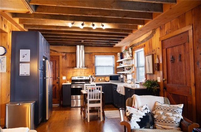 5681 Leidenfrost Adams Rd, Hector, NY 14841 - kitchen featuring appliances with stainless steel finishes, wall chimney range hood, wooden walls, beam ceiling, and dark wood-style floors