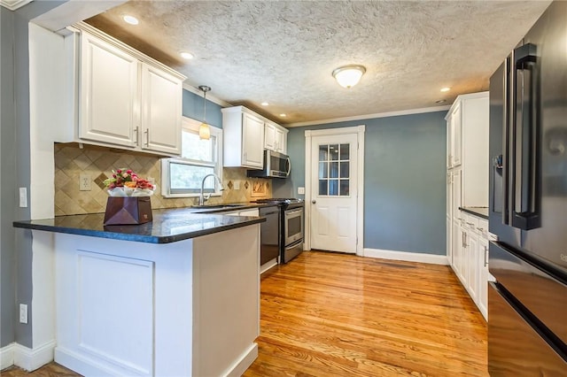 209 Thompson Rd, Henrietta, NY 14623 - kitchen featuring appliances with stainless steel finishes, a peninsula, white cabinets, backsplash, and light wood-type flooring