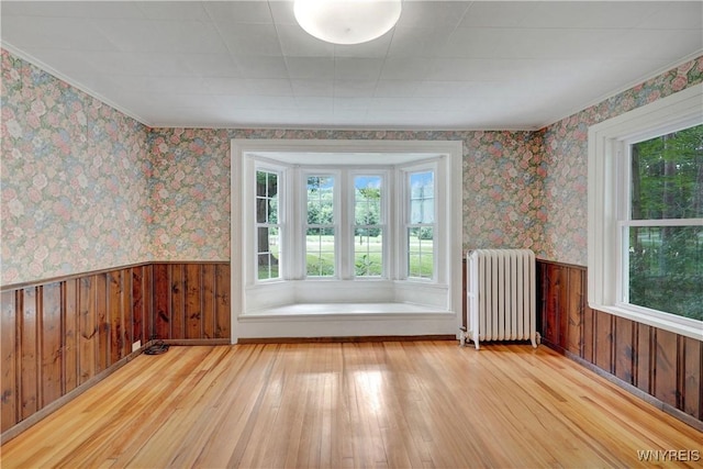 7709 Olean Rd, Holland, NY 14080 - empty room with radiator heating unit, wood-type flooring, wainscoting, wallpapered walls, and wood walls