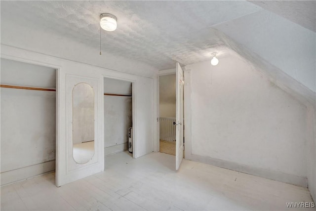 7709 Olean Rd, Holland, NY 14080 - unfurnished bedroom featuring two closets, a textured ceiling, and lofted ceiling