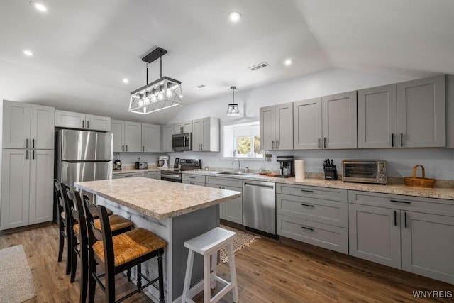 9184 Newcomb Rd, Evans, NY 14006 - kitchen with stainless steel appliances, lofted ceiling, gray cabinetry, a breakfast bar area, and light countertops