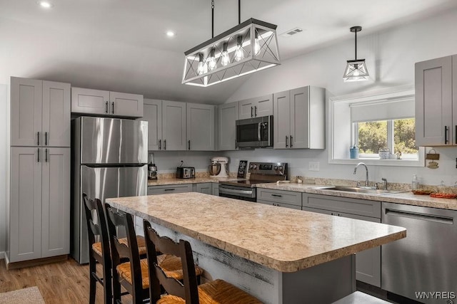 9184 Newcomb Rd, Evans, NY 14006 - kitchen with stainless steel appliances, gray cabinetry, vaulted ceiling, a breakfast bar, and light countertops