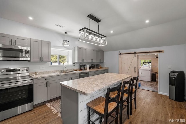 9184 Newcomb Rd, Evans, NY 14006 - kitchen with appliances with stainless steel finishes, washer / dryer, gray cabinetry, a barn door, and light countertops