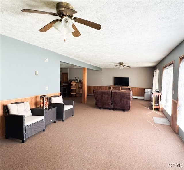1155 County Route 53, Scriba, NY 13126 - carpeted living room featuring ceiling fan, a textured ceiling, wainscoting, and wooden walls